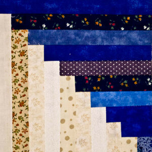 Cornered Log Cabin quilt block image pieced with scraps of different blue and beige fabrics